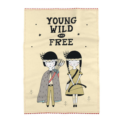 Tea towel printed on a cream ground, reading Young, wild and free, above two children in feathered headbands, one in a fringed cape, carrying a bow and arrows