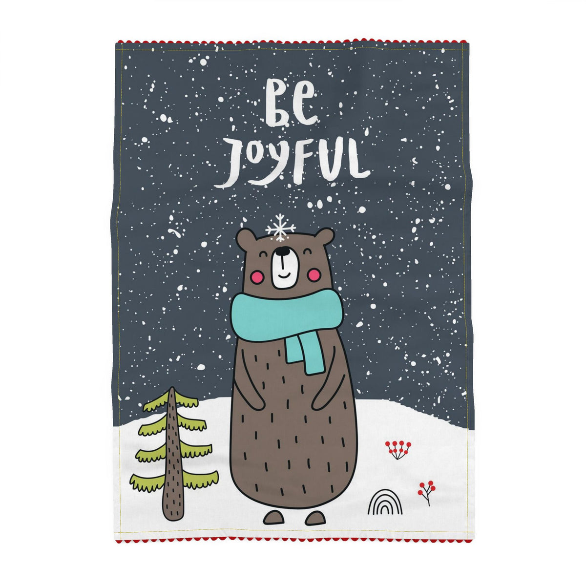 Tea towel printed on a slate-grey ground, reading Be Joyful, above a brown bear in a teal scarf standing in falling snow beside a small fir tree