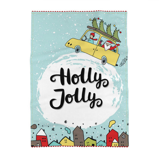 Illustrated Christmas tea towel. A yellow car flies through falling snow with a fir tree strapped to the roof and Santa waving from the back, a row of red, teal and mustard houses below. Printed and sewn in England, 70 × 50 cm, £29.95 with free UK delivery. Made to be given. Made to be kept.